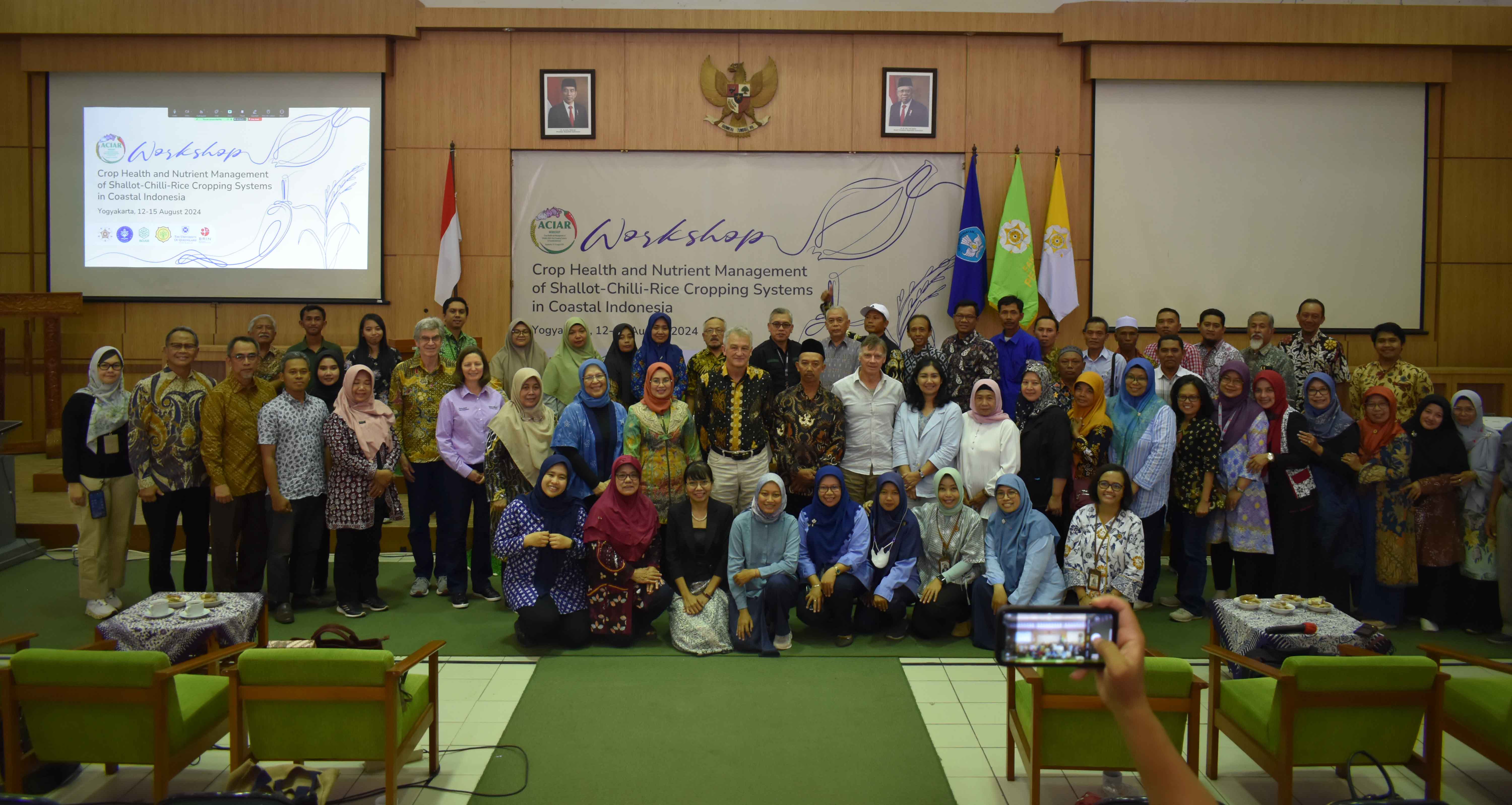 Group of people in a room lined up in front of a wall smiling